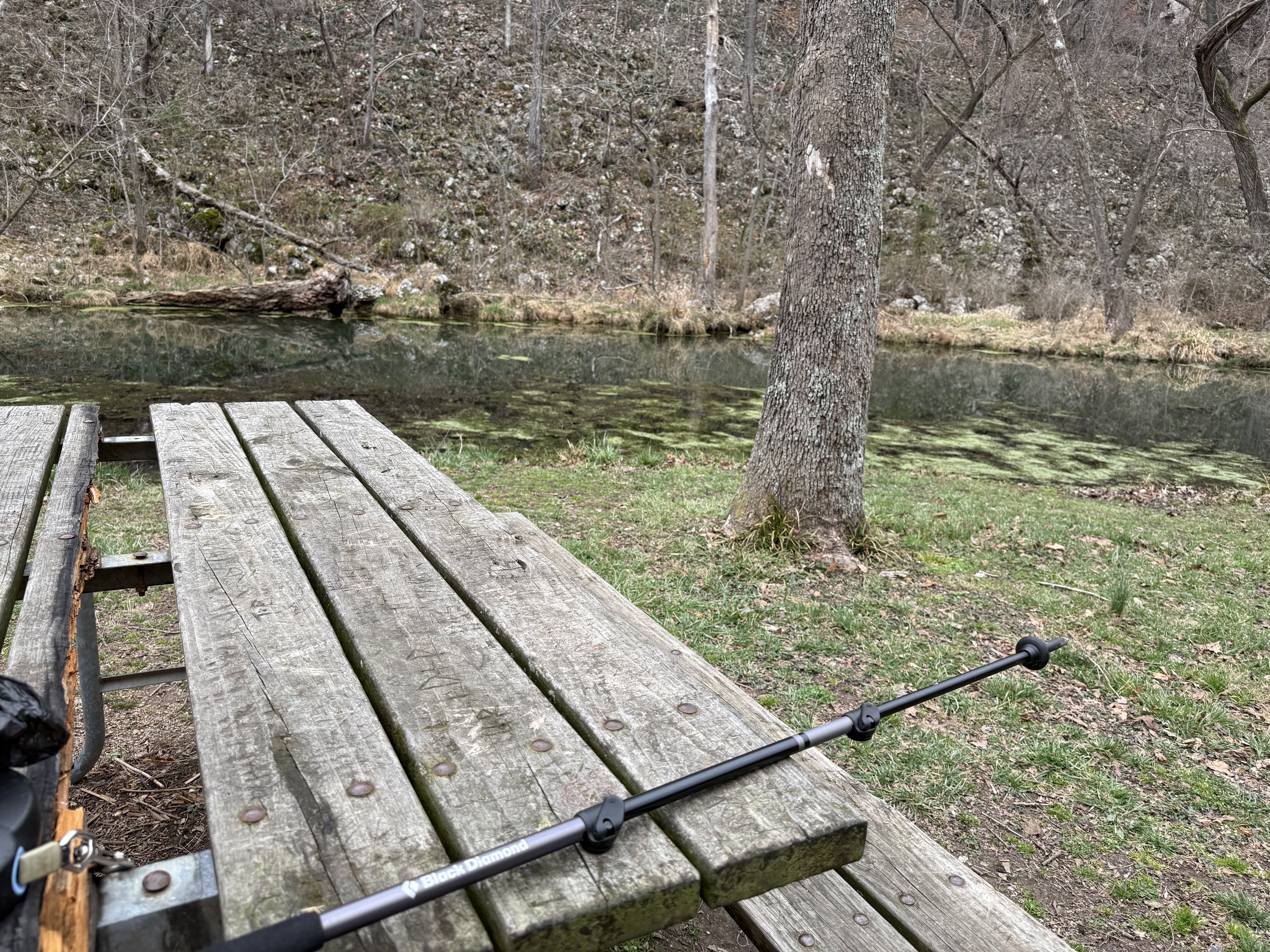 Hiking poles on picnic table, creek and trail in background
