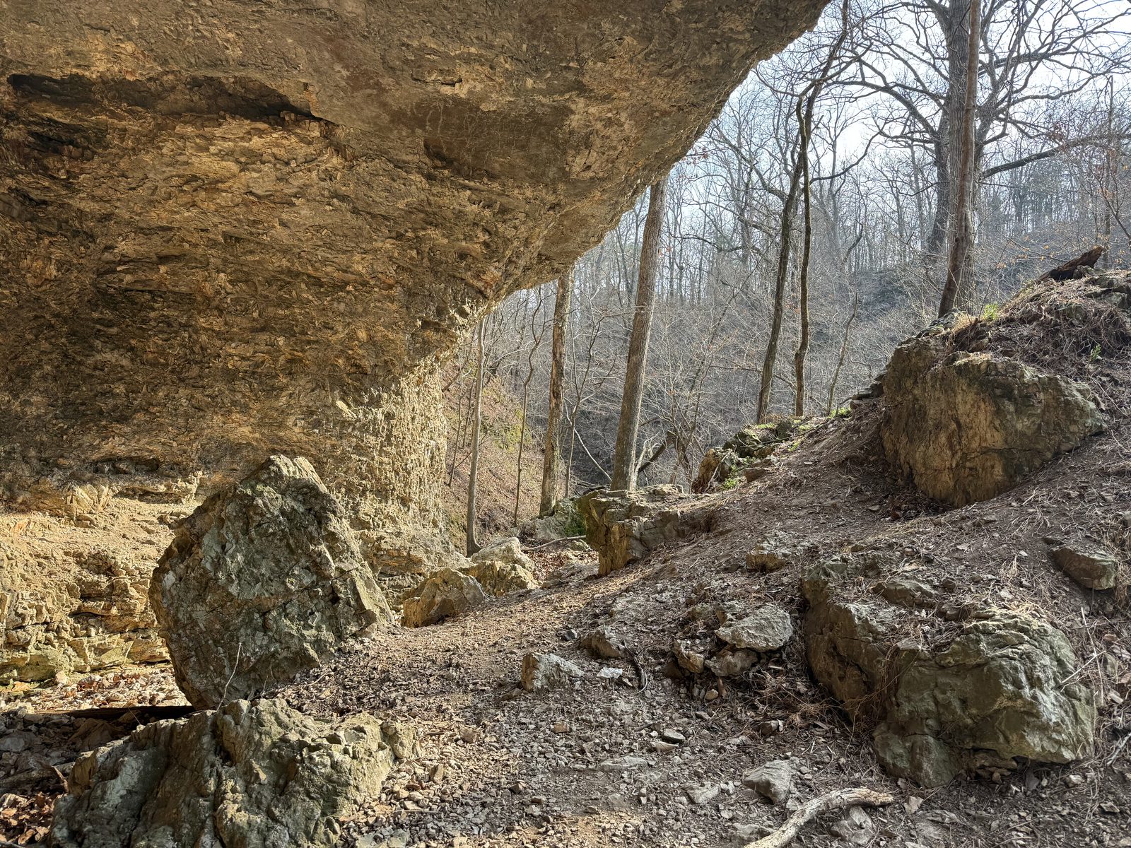 Large rock overhang shelter cave with massive fallen boulders underneath a sandstone ceiling